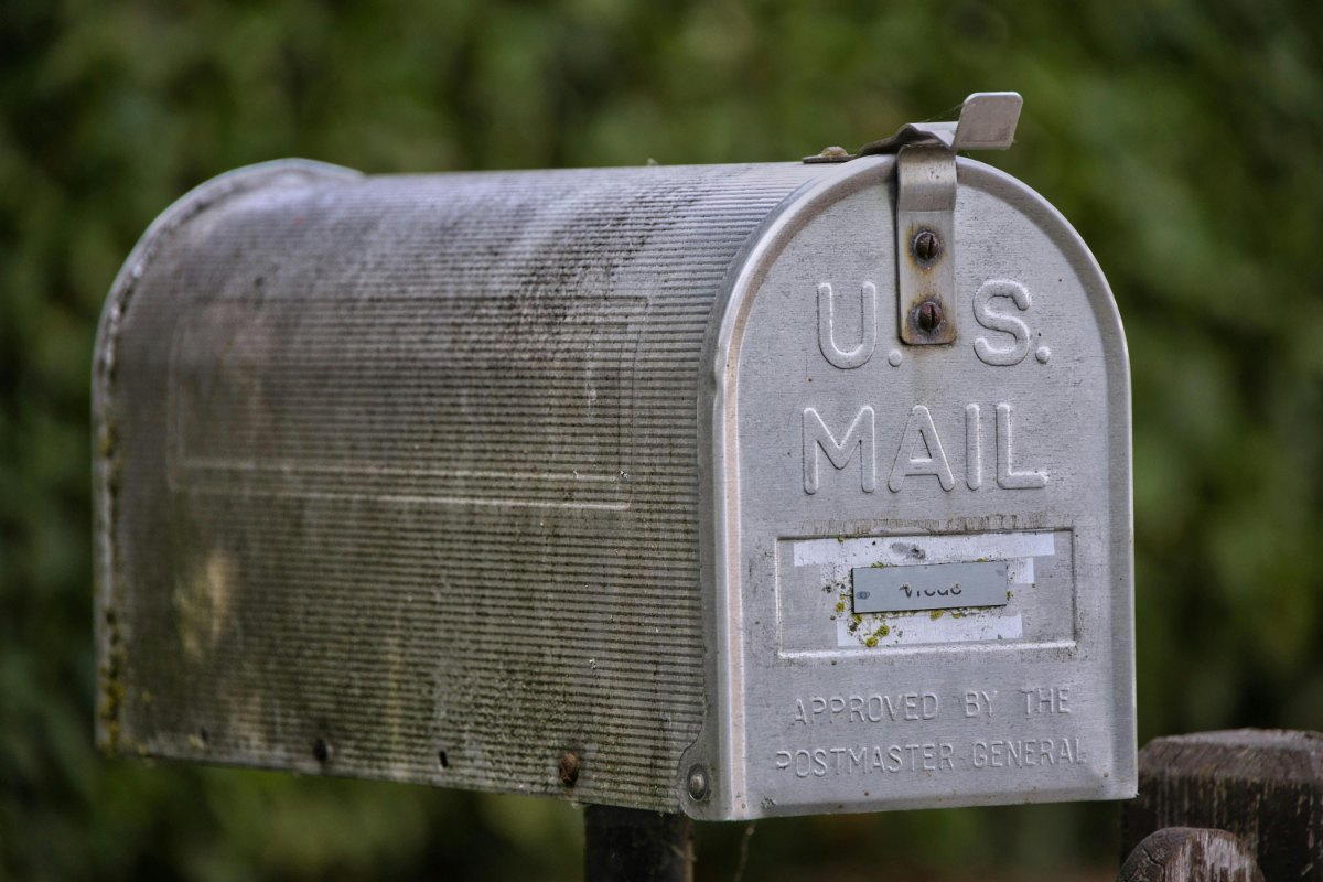 A focused compliance officer in a professional Charlotte bank, using a 10x jeweler's loupe to verify the crisp microprinted signatures on a roll of authentic 2024 US Flag Forever stamps.