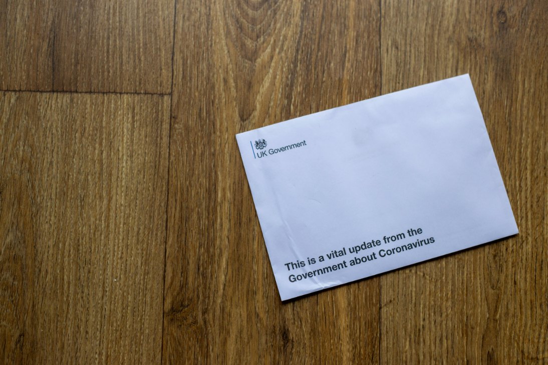 A wedding planner in a candlelit studio pressing a custom wax seal onto an invitation, with a sheet of non-machinable butterfly stamps ready for use.
