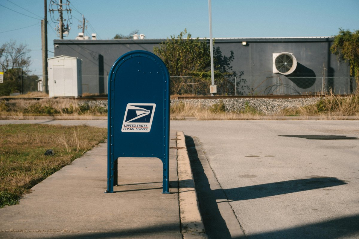 A marketing manager observing a residential mailbox area to understand the disparity in open rates between first-class stamped mail and standard permit-imprint mail.