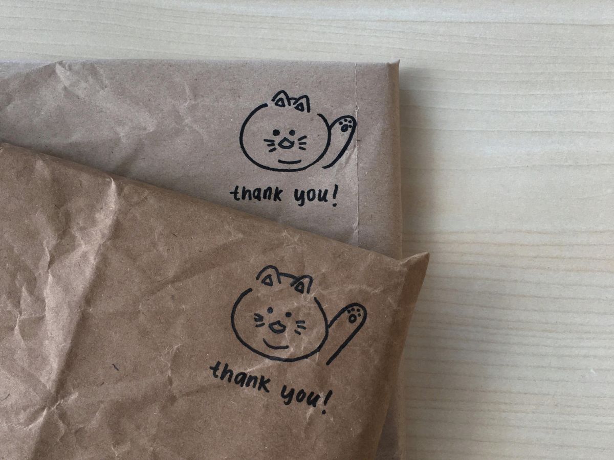 A dedicated PTA mom in a school library sorting stacks of silent auction invitations and applying bulk stamps to maximize the fundraising budget.