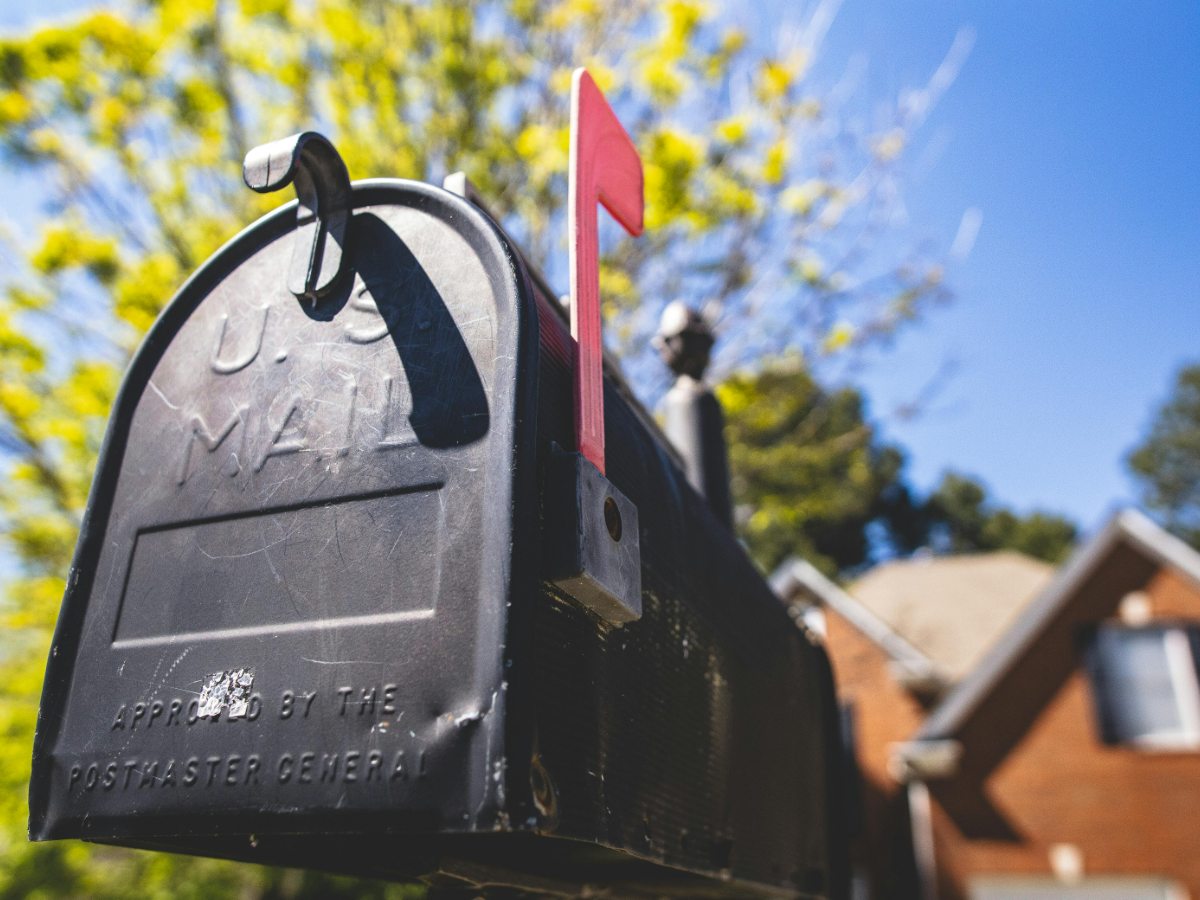 A private equity operations lead in a Seattle office auditing a batch of merger announcement kits and applying bulk first class postage stamps for sale from a professional coil with the city skyline in the background.