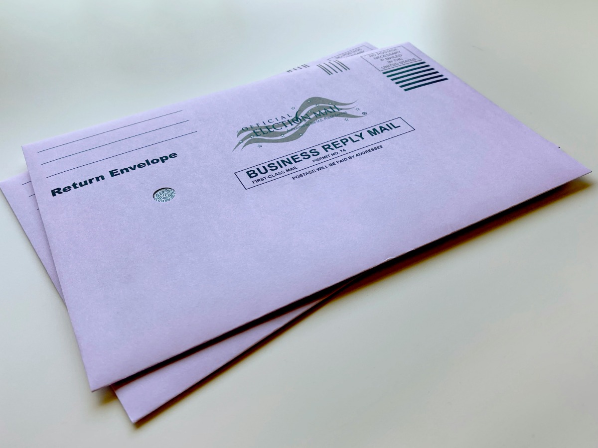 A legal clerk in Charlotte auditing a batch of discovery bundles and applying forever stamps while verifying court deadlines in a high-rise law office.