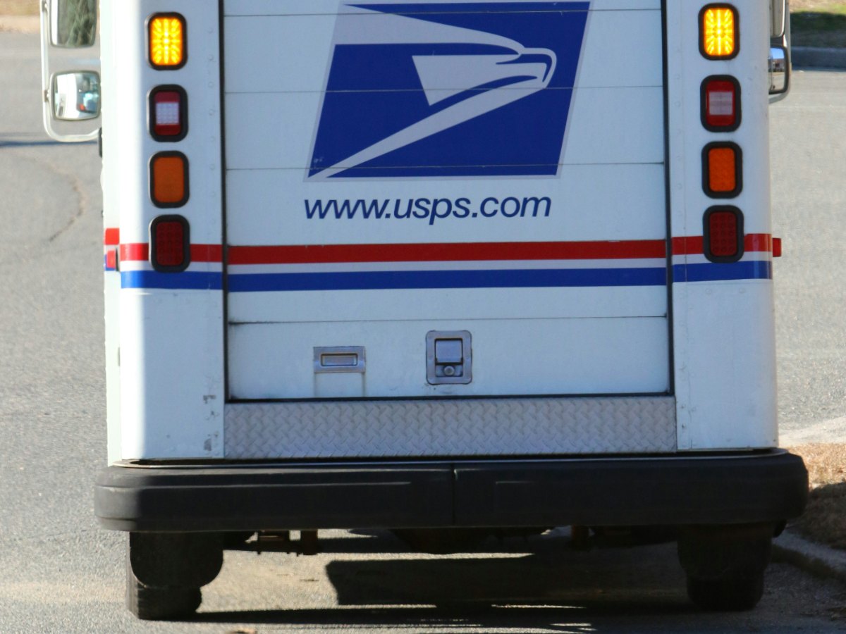 A medical research lead in his Minneapolis lab auditing a batch of clinical recruitment kits and verifying a tracking usps stamp orders manifest with a laboratory setting in the background.